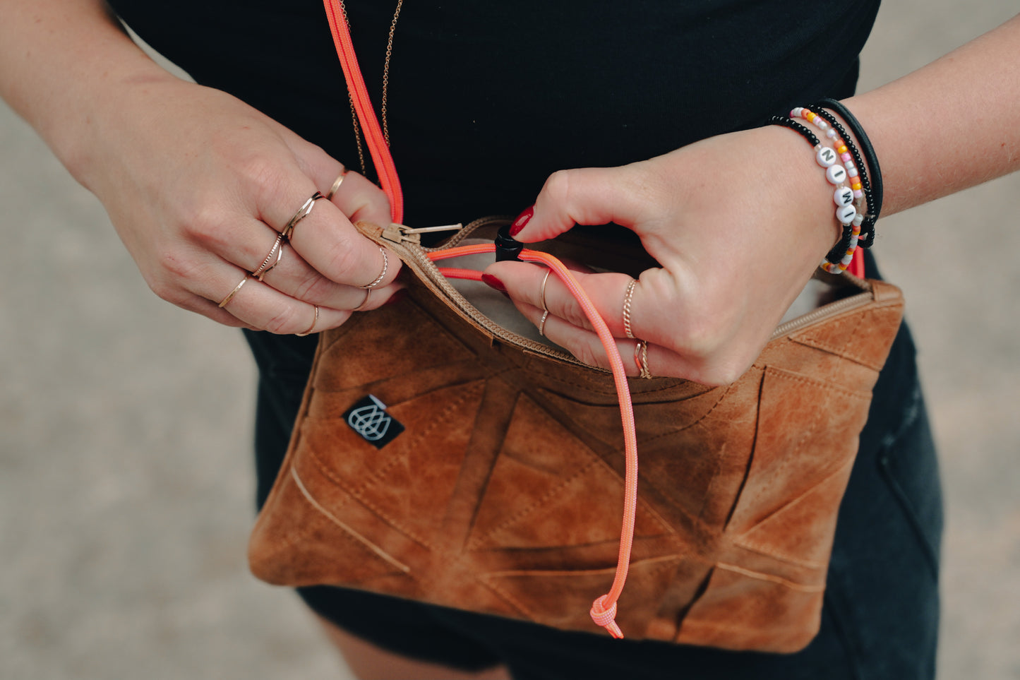 Frau verstellt die Länge der Bänder der Festivaltasche mit dem Kordelstopper in der Tasche